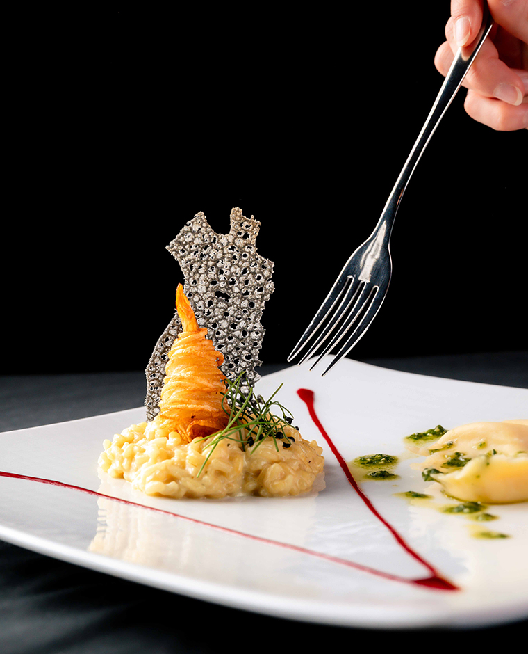 Exquisiter kulinarischer Genuss im Hotel Tannenhof: Risotto mit Garnelen und Ravioli, angerichtet auf einem weißen Teller.